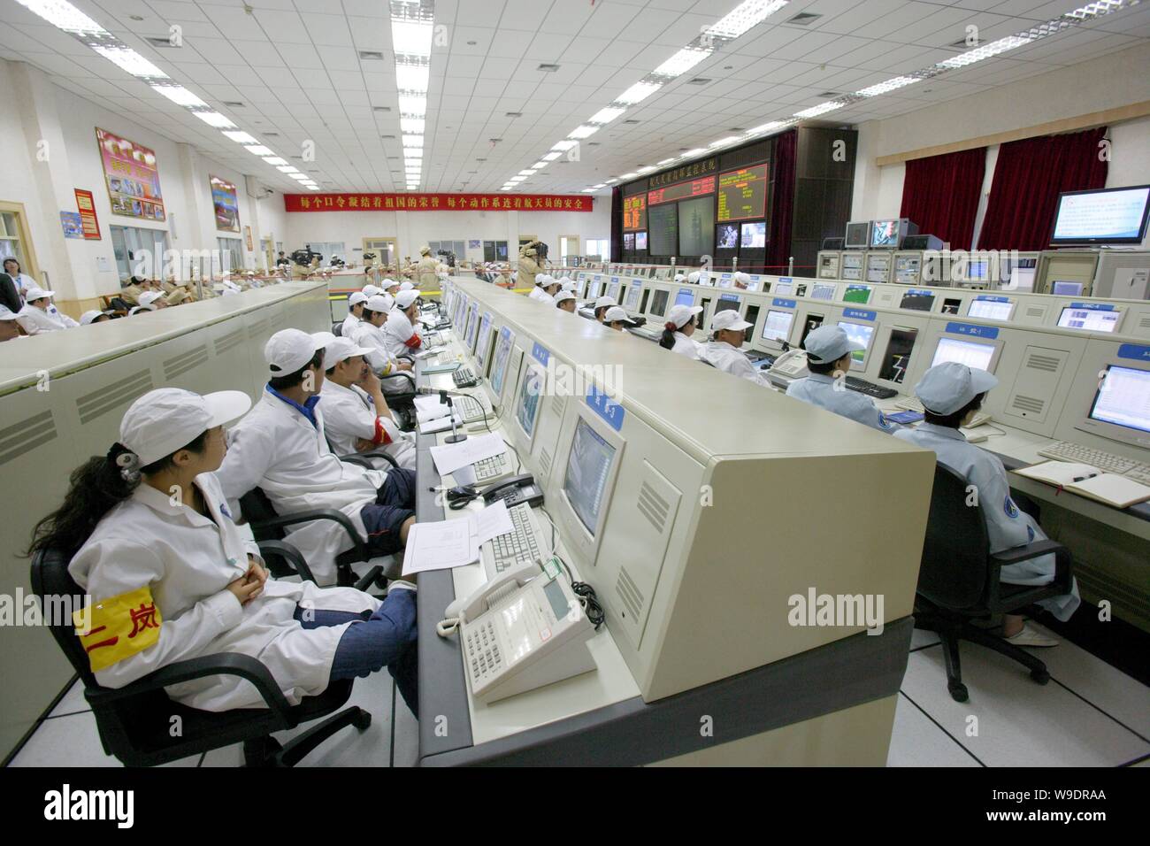 Chinese aeronautical scientists and workers monitor screens in a control and display center during the last joint testing for the Shenzhou VII manned Stock Photo