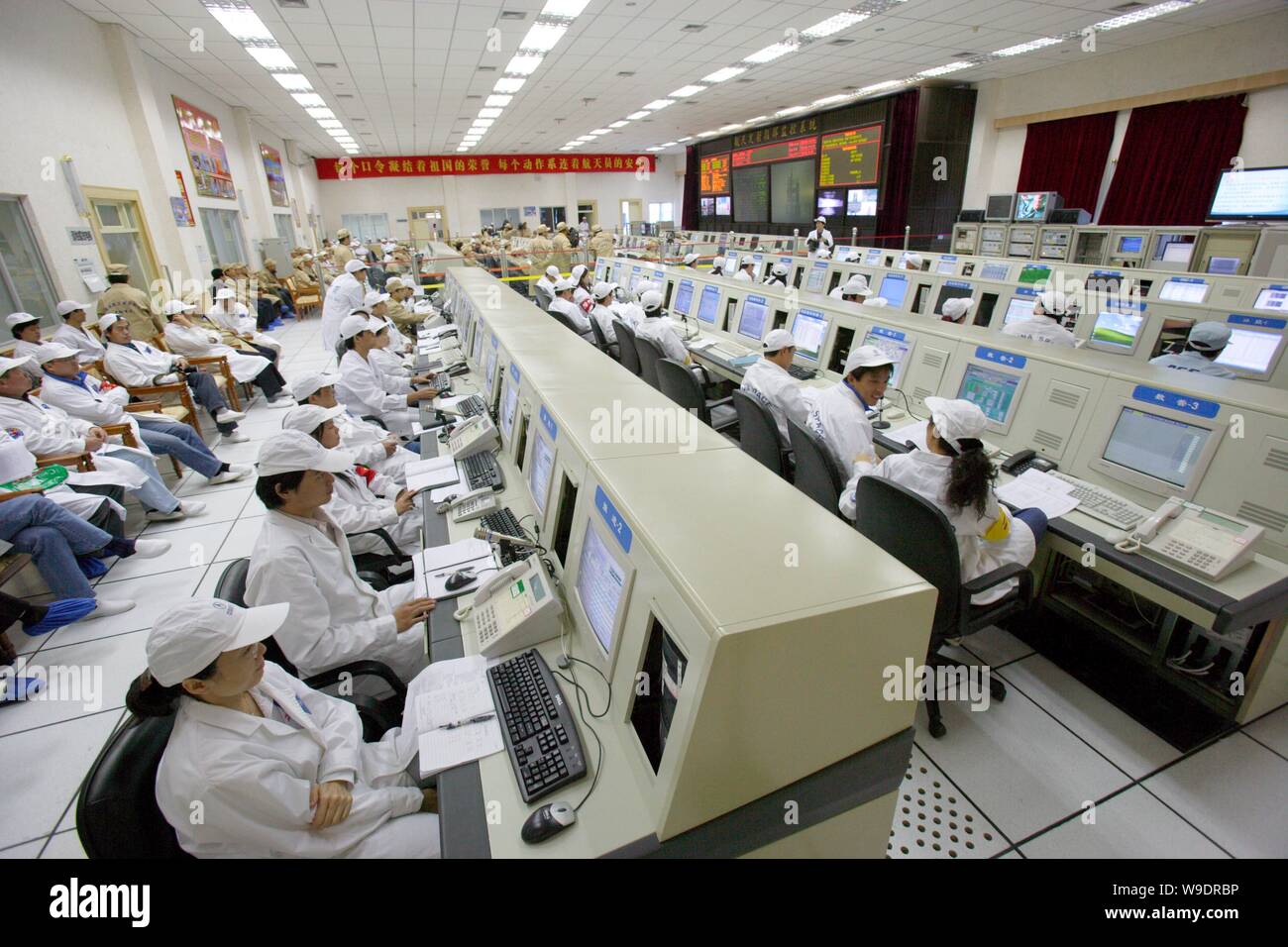 Chinese aeronautical scientists and workers monitor screens in a control and display center during the last joint testing for the Shenzhou VII manned Stock Photo
