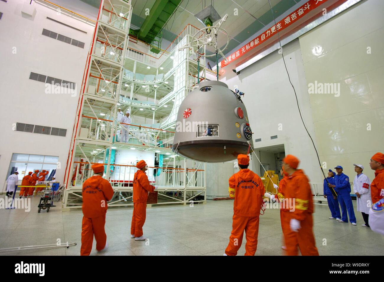 Chinese aeronautical scientists lift the re-entry module (capsule) to assemble it with the propelling module (capsule) of the Shenzhou VII manned spac Stock Photo