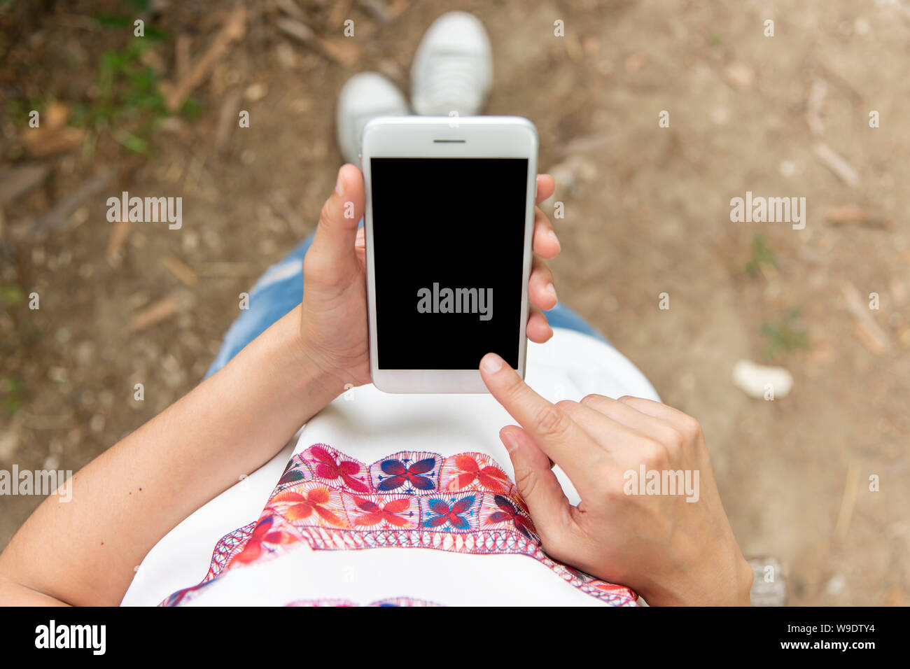 top view of a young woman watching her mobile and pressing the screen Stock Photo