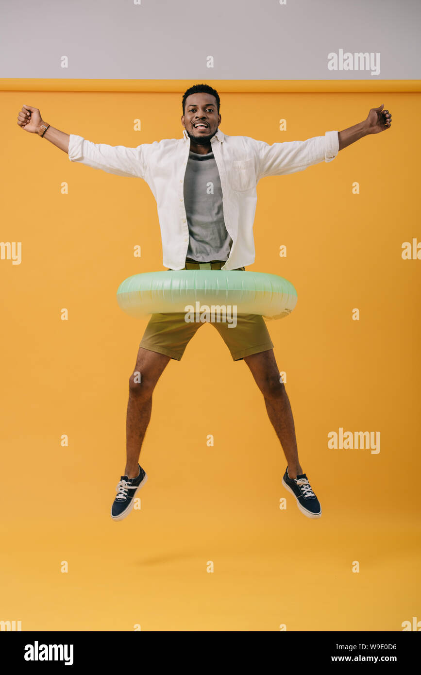 happy african american man jumping with swim ring on orange Stock Photo