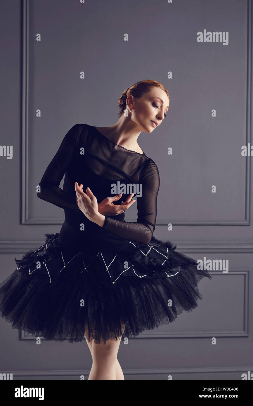 Ballerina in a black tutu posing on a black background. Concept ballet