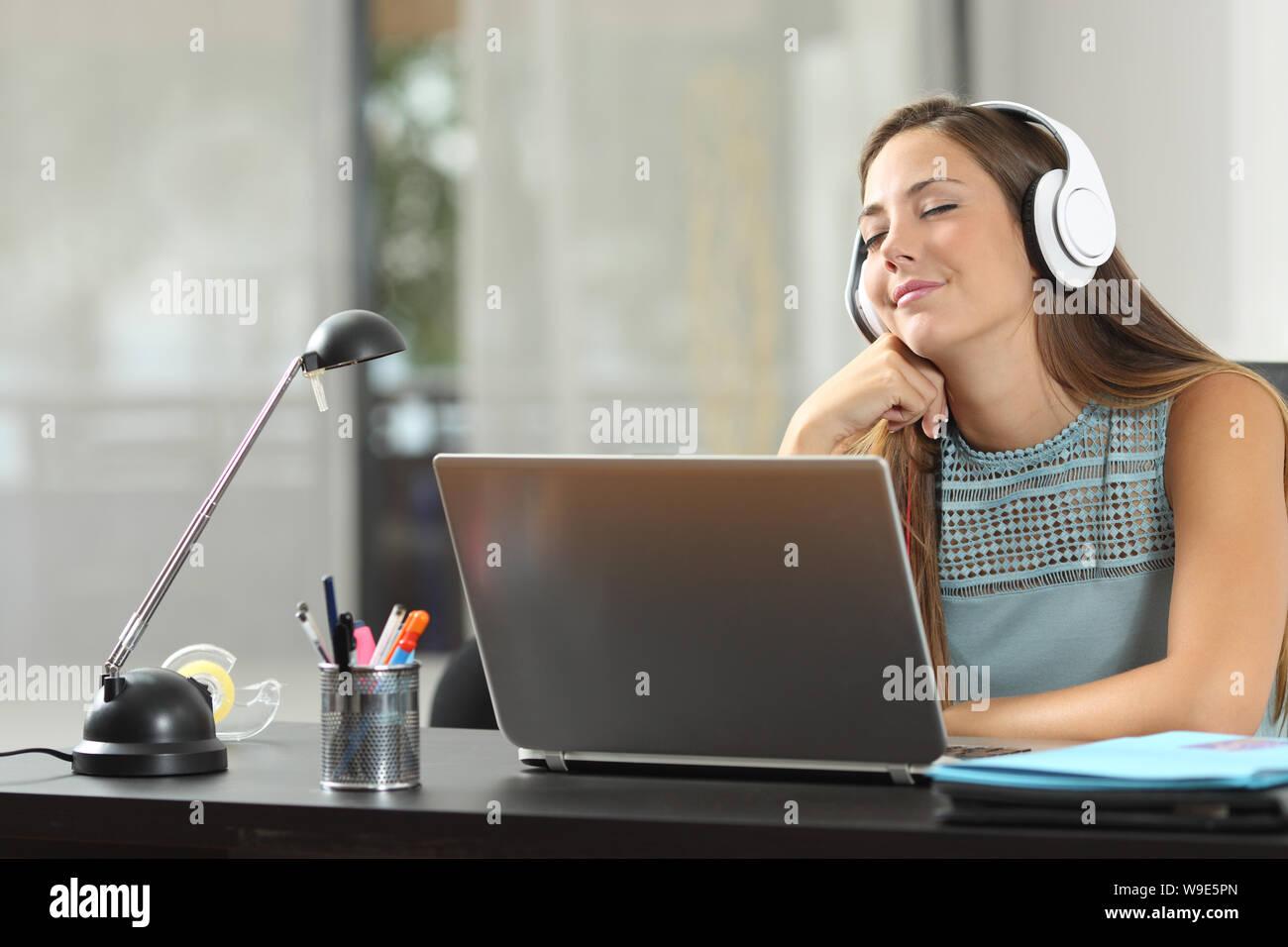 Happy girl listening to music wearing headphones in a room Stock Photo