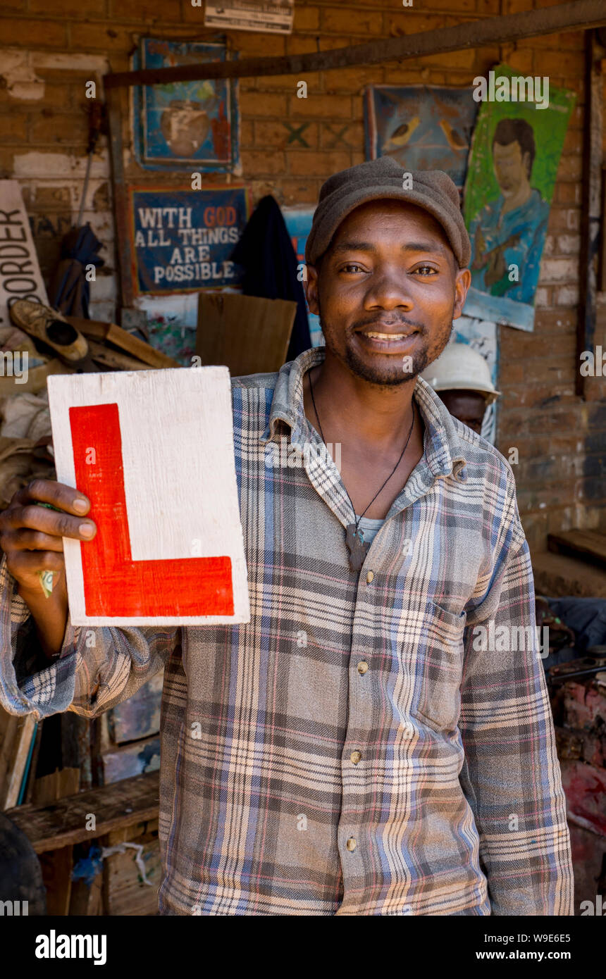 Man in Mzuzu market, Malawi, sells homemade learner plate for cars Stock Photo
