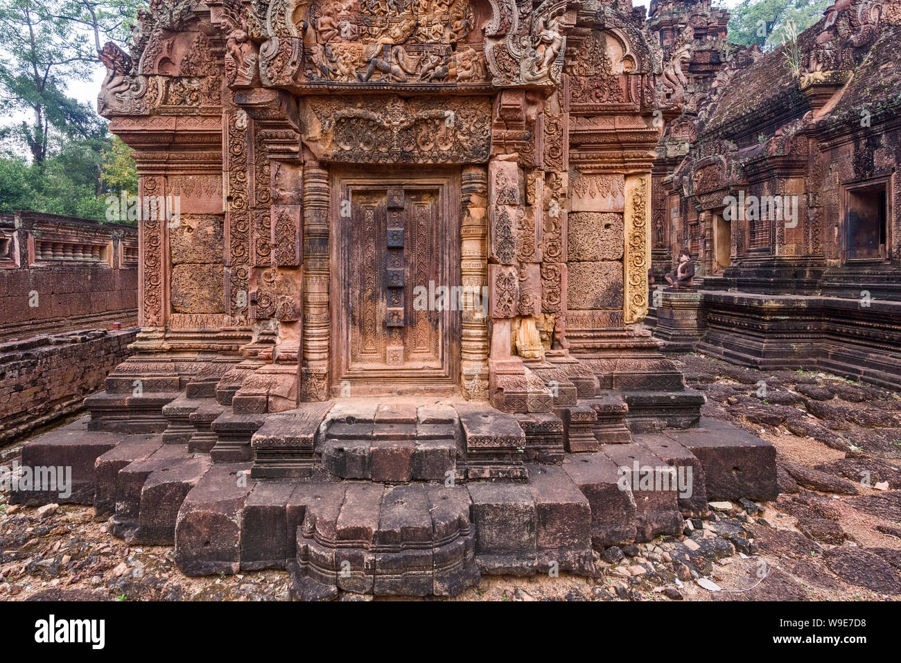 Blind door, balusters and devatas carved into the red sandstone walls ...