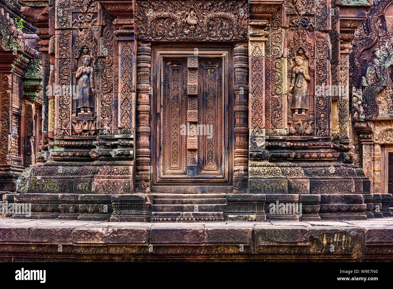 Blind door, balusters and devatas carved into the red sandstone walls ...