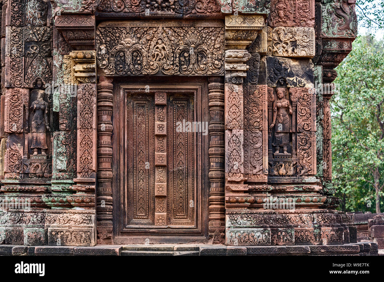 Blind door, balusters and devatas carved into the red sandstone walls ...
