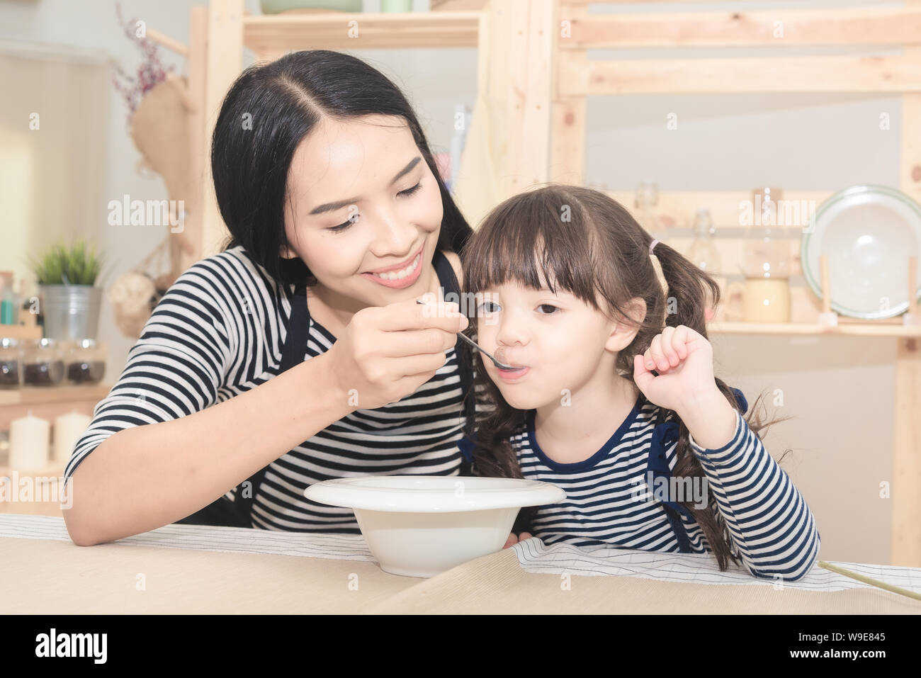 https://c8.alamy.com/comp/W9E845/happy-family-of-asian-mom-feeding-healthy-breakfast-to-her-cute-daughter-in-the-morning-photo-series-of-family-kids-and-happy-people-concept-W9E845.jpg