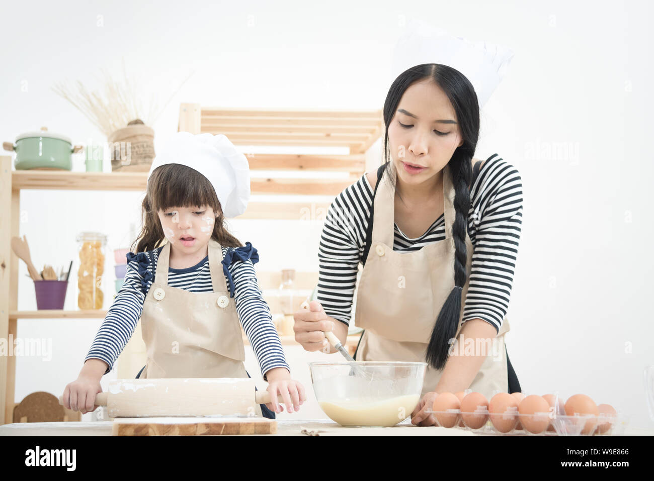 Asian mother and her daughter are preparing the dough to make a cake in the kitchen room on vacation.Photo series of Happy family concept. Stock Photo