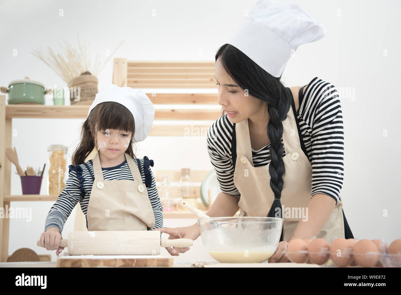 Asian mother and her daughter are preparing the dough to make a cake in the kitchen room on vacation.Photo series of Happy family concept. Stock Photo
