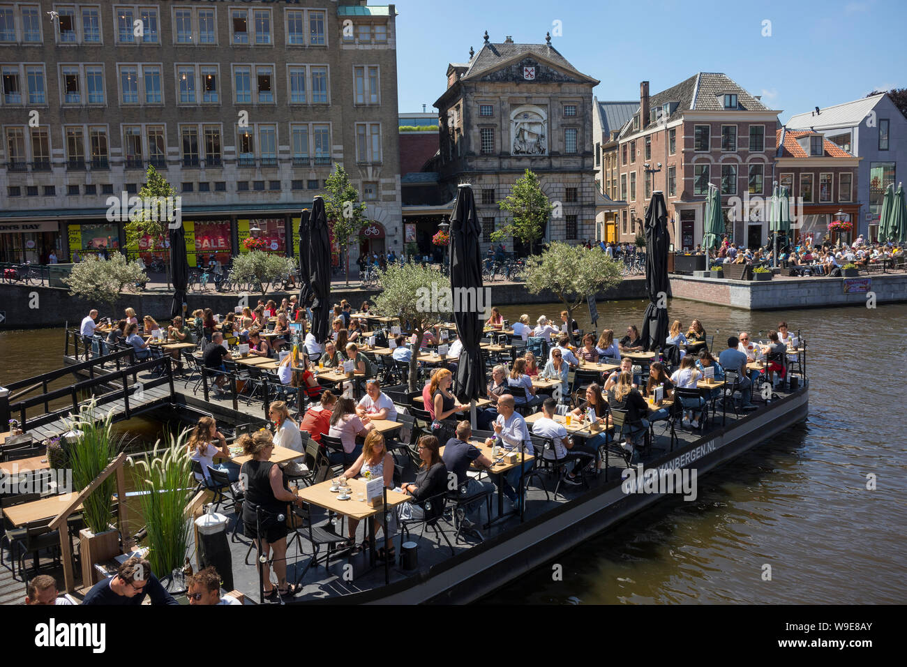 Leiden, Holland - July 05, 2019: Restaurant terrace on boats at the crossing of the Oude and Nieuwe Rijn opposite the Weigh House Stock Photo