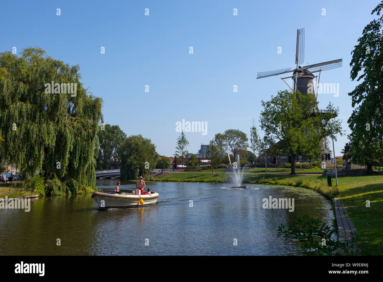 Leiden, Holland - July 26, 2019: Sailing a recreational boat with the historical tower mill de Valk, the Falcon, in the background Stock Photo