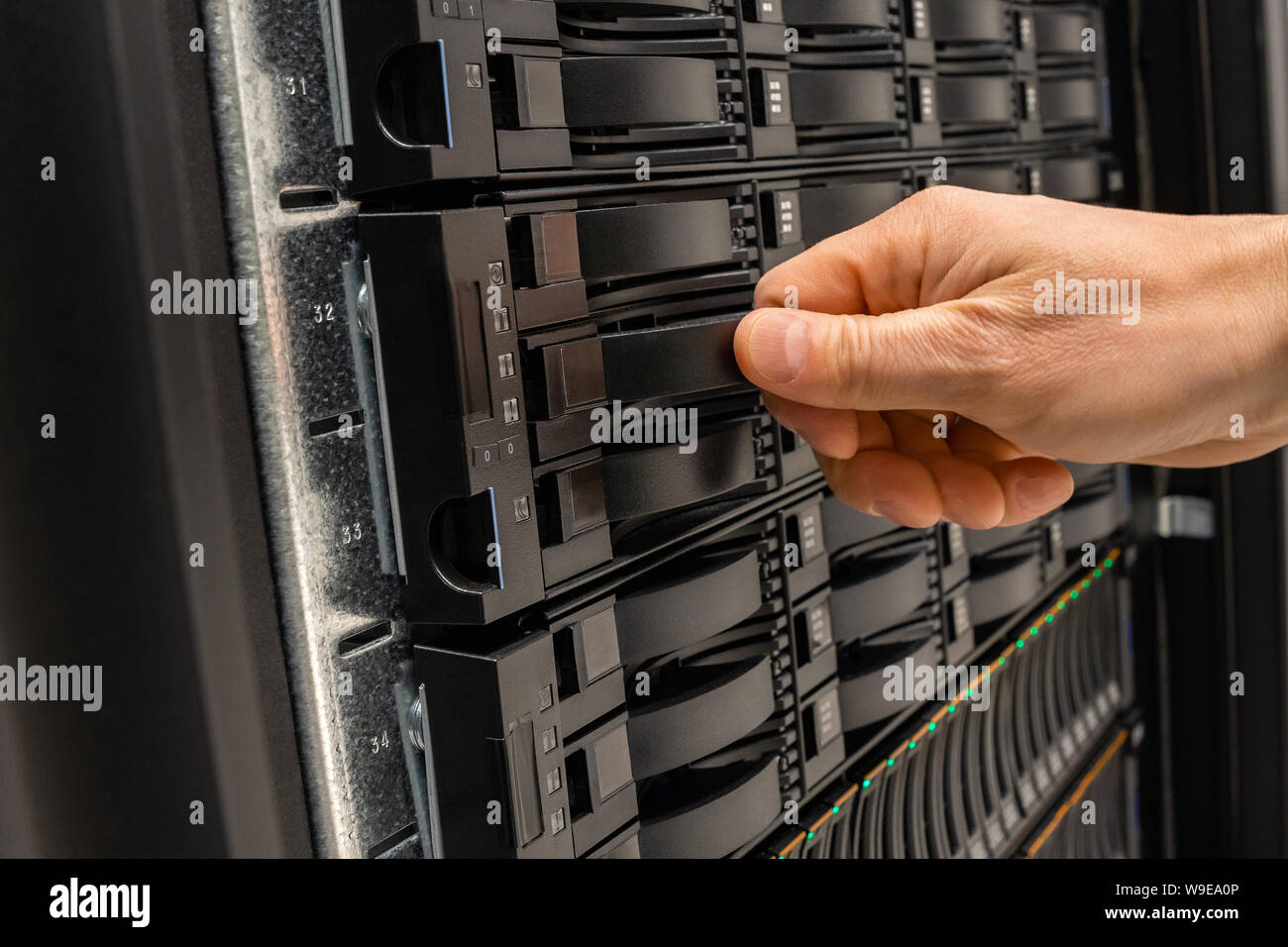 Male IT Engineer Replacing Server Drive in SAN At Datacenter Stock Photo