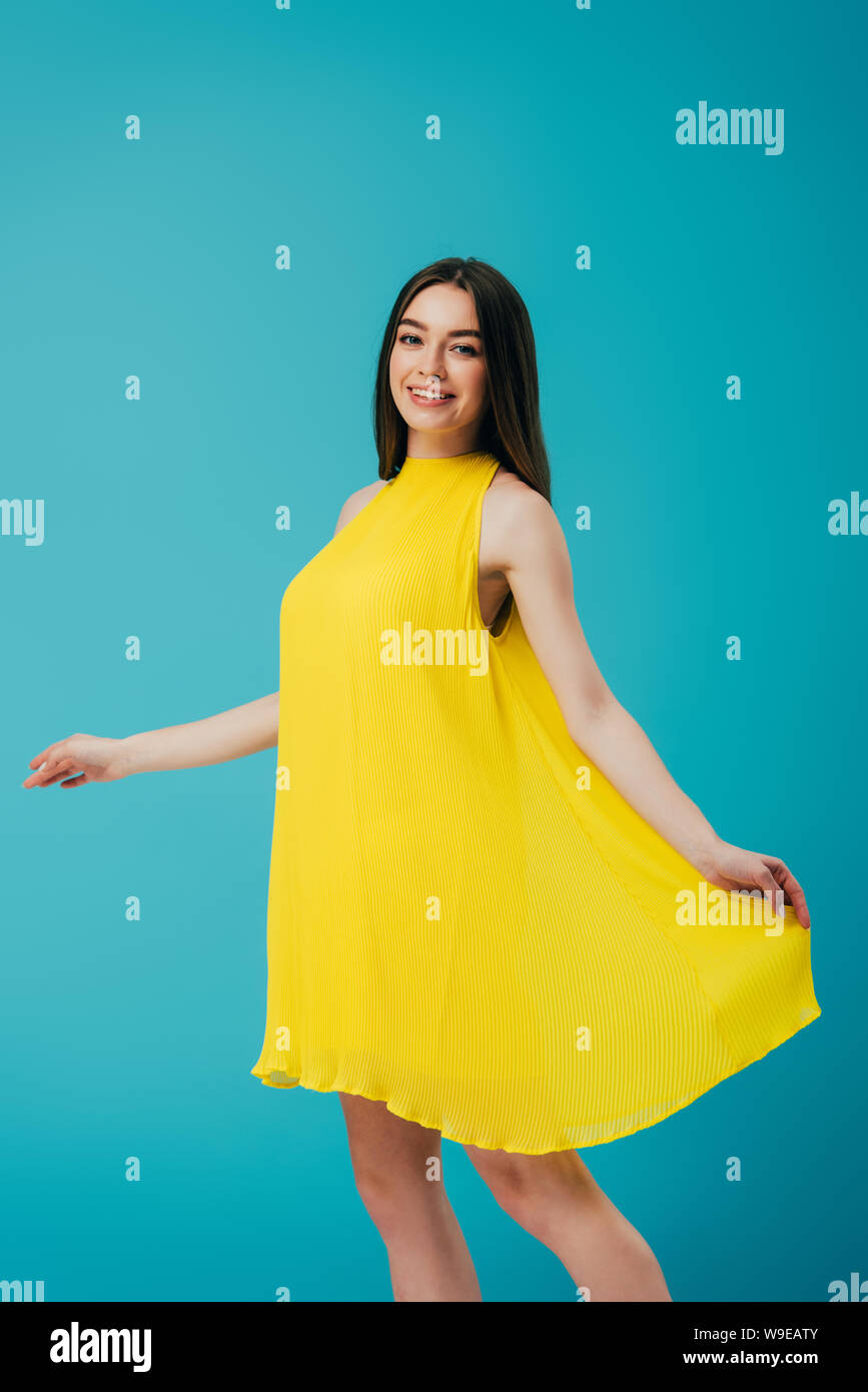 happy smiling beautiful girl in yellow dress isolated on turquoise ...