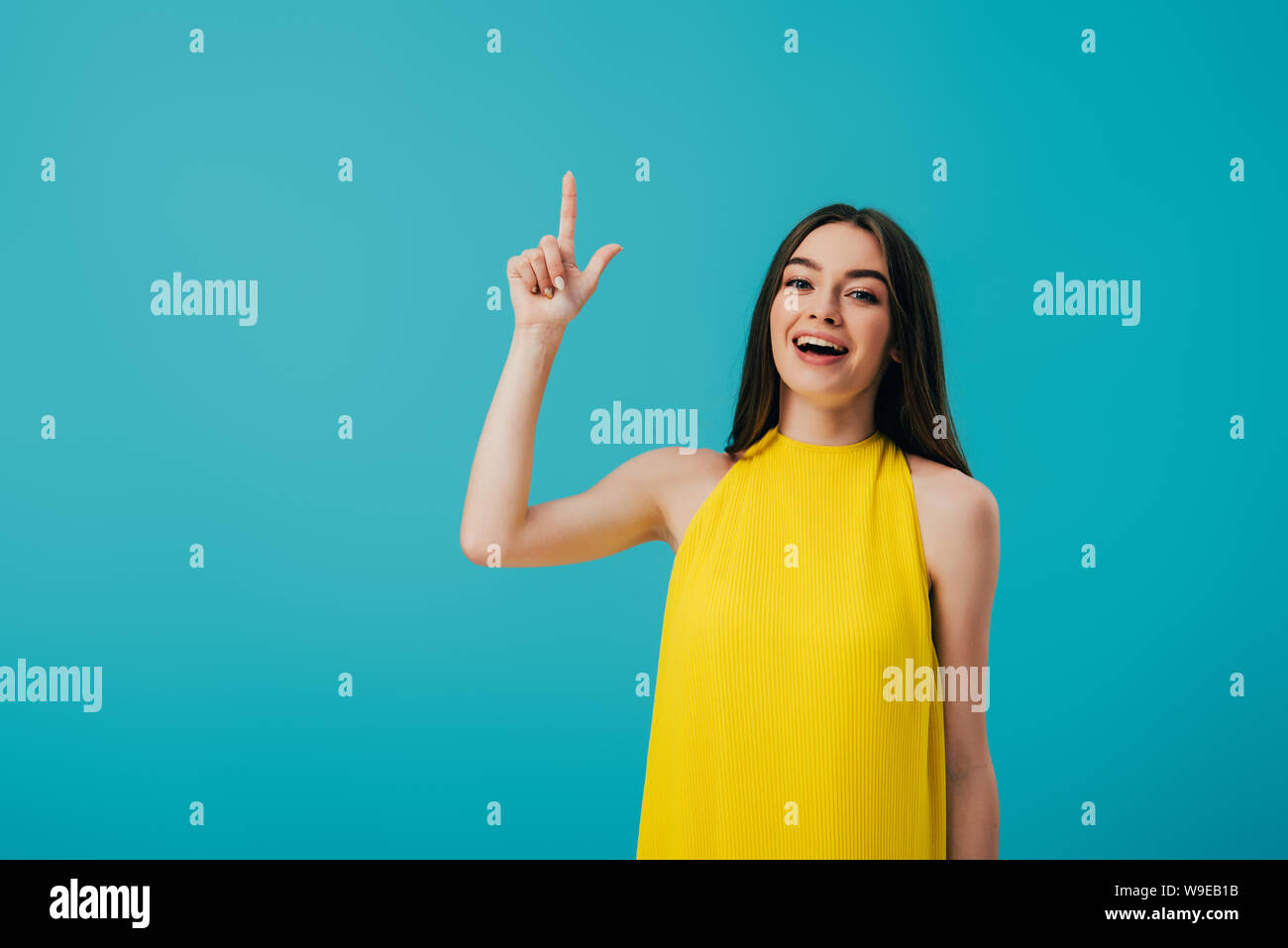 excited beautiful girl in yellow dress pointing with finger upwards ...
