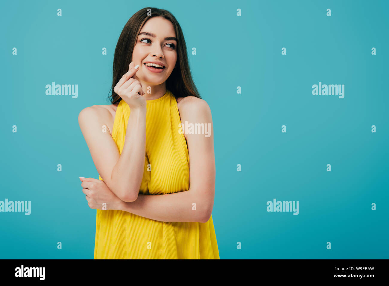 happy brunette girl in yellow dress snapping fingers isolated on ...