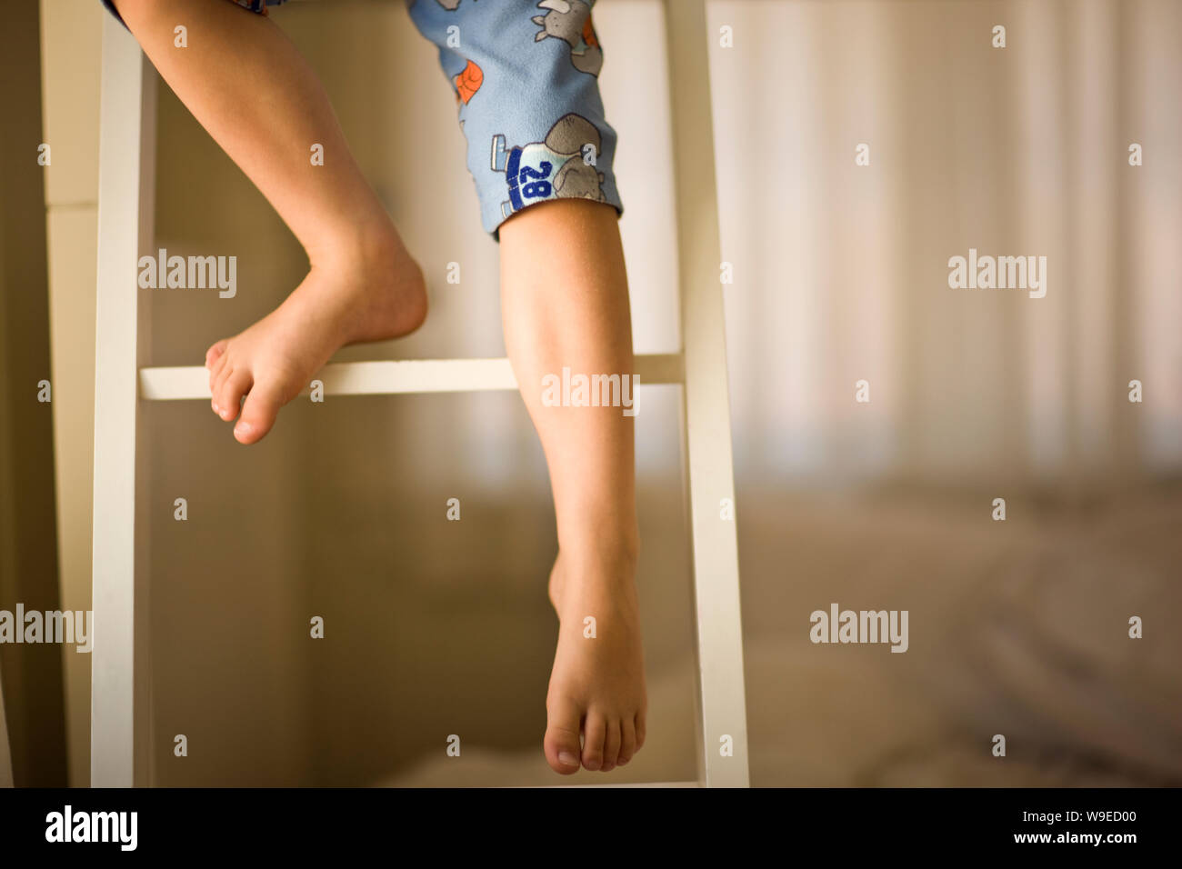 Boy climbing down the ladder of a bunk bed inside his bedroom. Stock Photo