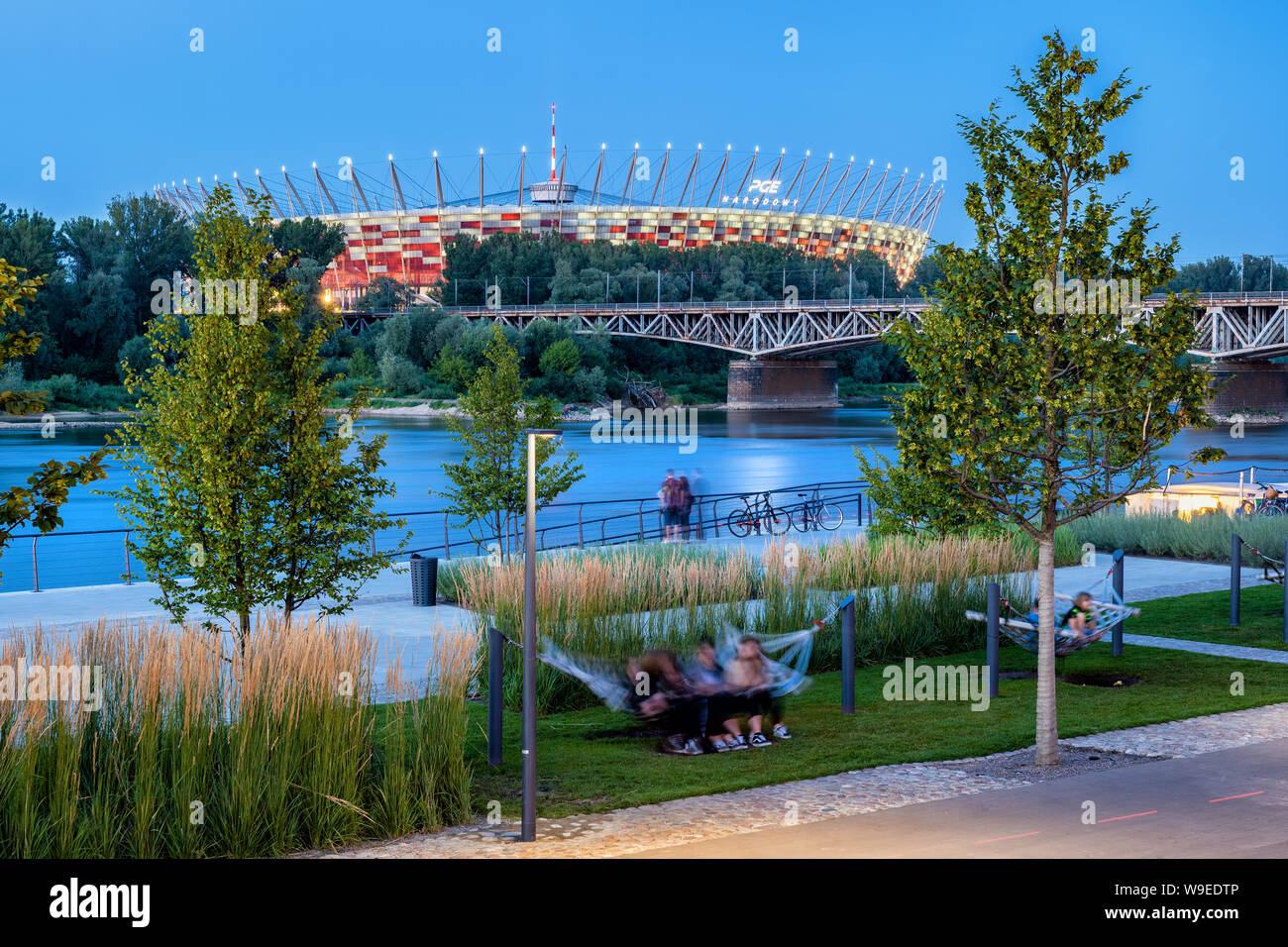Poland, capital city of Warsaw, people relax on hammocks on the Vistula River boulevards with view to the National Stadium in the evening Stock Photo