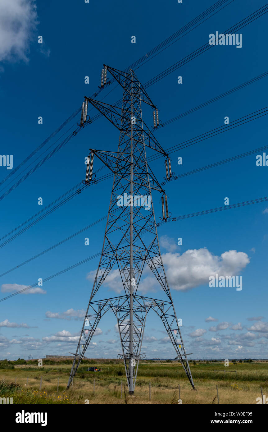 Overhead electricity power cables on a pylon against a blue sky Stock Photo
