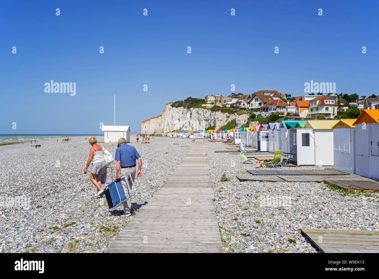 Sunbathers and colourful beach cabins on shingle beach / pebble beach at Criel-sur-Mer in summer, Seine-Maritime, Normandy, France Stock Photo