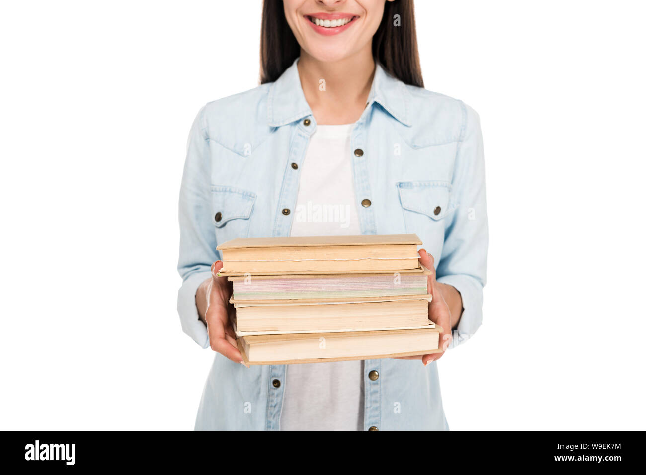 cropped view of smiling brunette girl in denim jacket holding books isolated on white Stock Photo