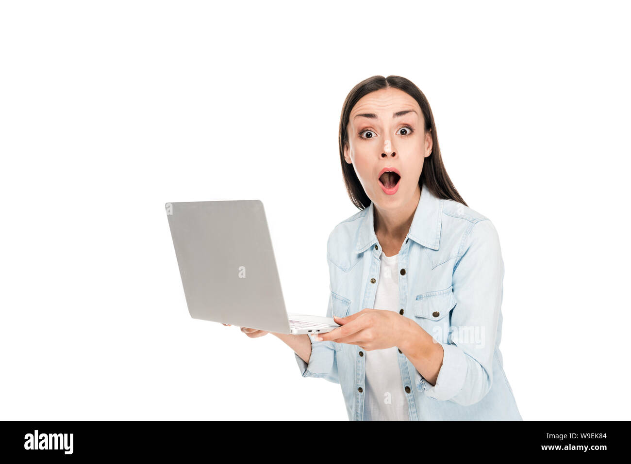 shocked girl in denim jacket holding laptop isolated on white Stock Photo