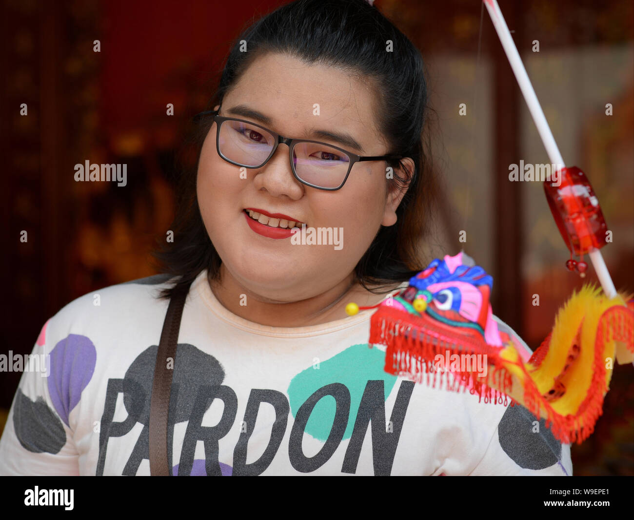 Full-figured young Thai woman poses with a paper puppet of a traditional Chinese lion, during Chinese New Year 2019. Stock Photo