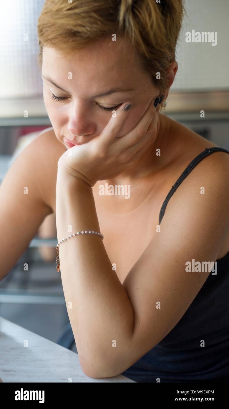Portrait of a beautiful mid-thirties woman with short light hair and bracelet, elbow leaning against the table Stock Photo