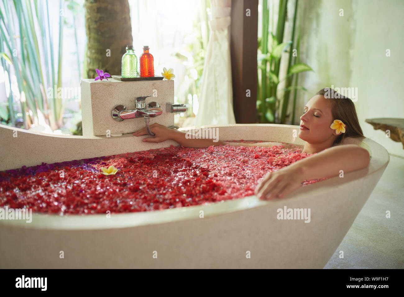Natural millennial woman being pampered in luxurious white bathtub