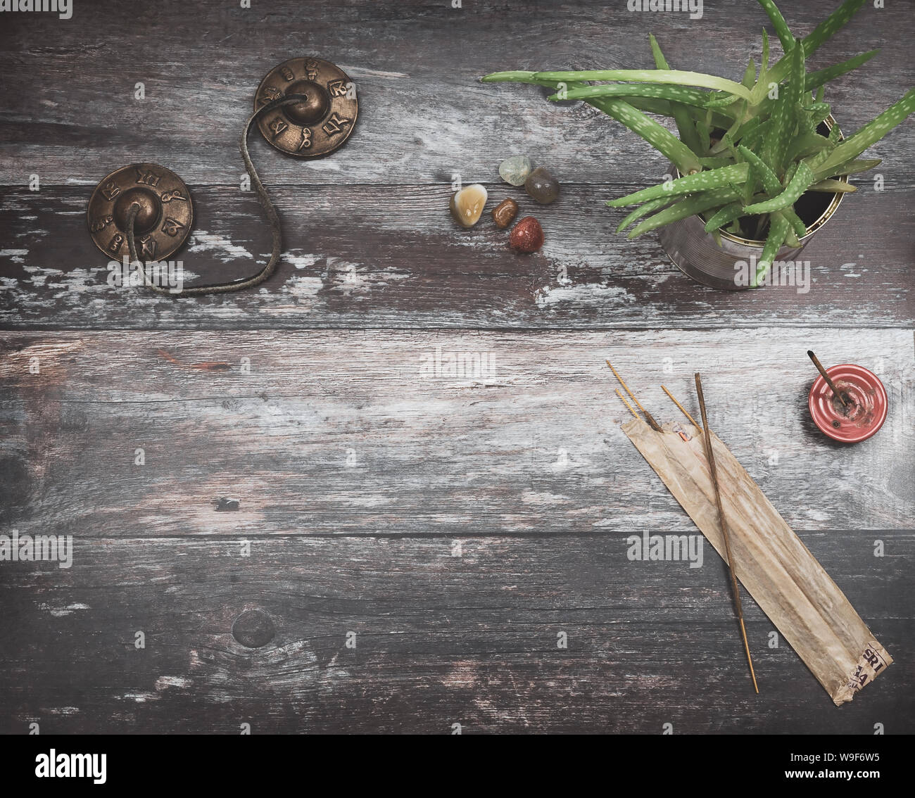 Rustic wooden table for text copy,  with green aloe vera plant, burning incense, incense sticks, small rounded energy healing stones in earthy colors Stock Photo