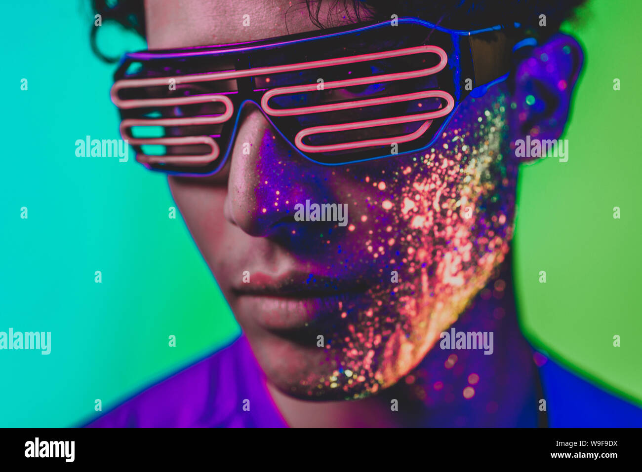 Handsome boy dancing at the rave party with fluorescent paintings on ...