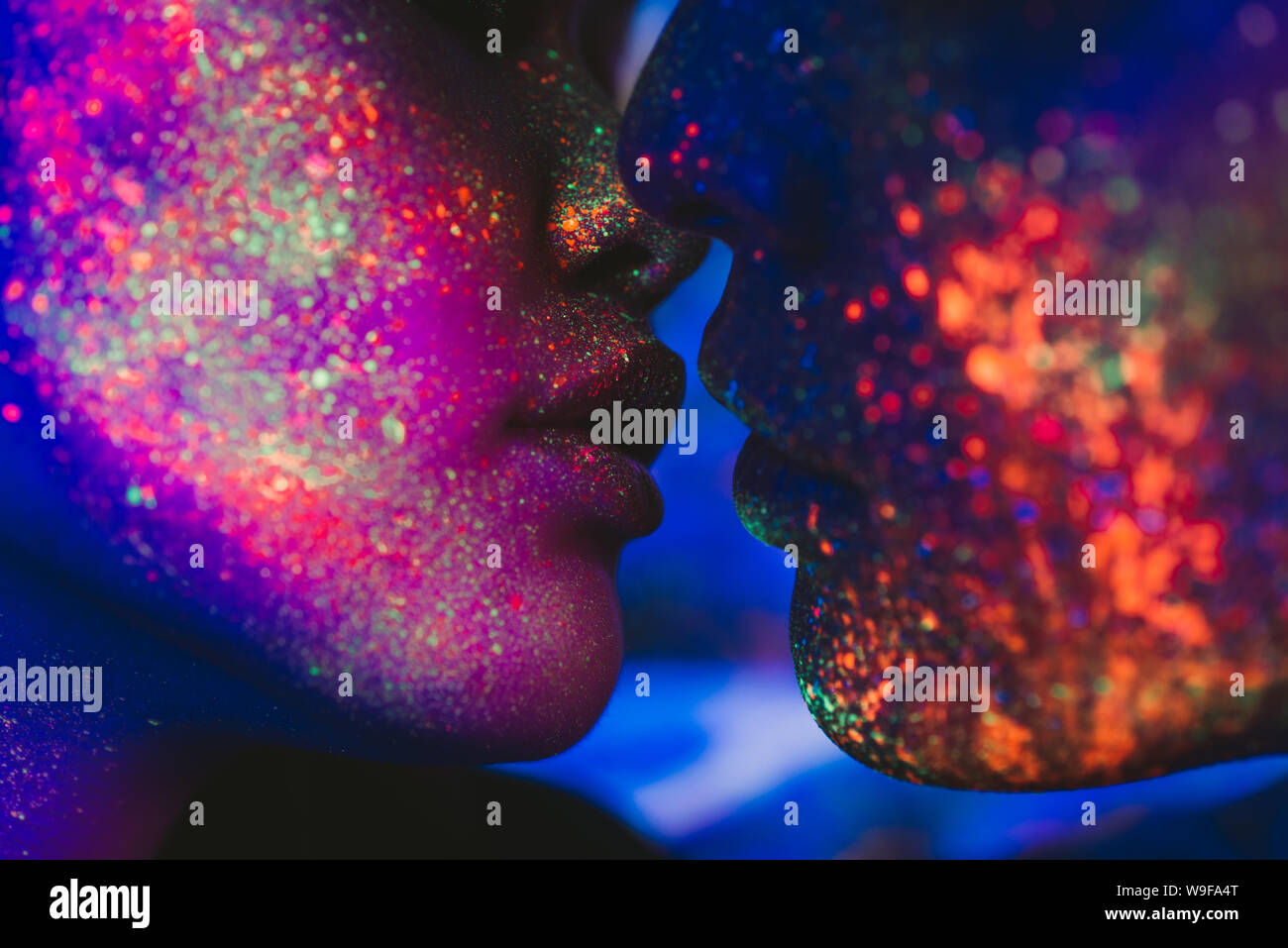 Couple kissing in the disco club with fluorescent paintings on the faces Stock Photo