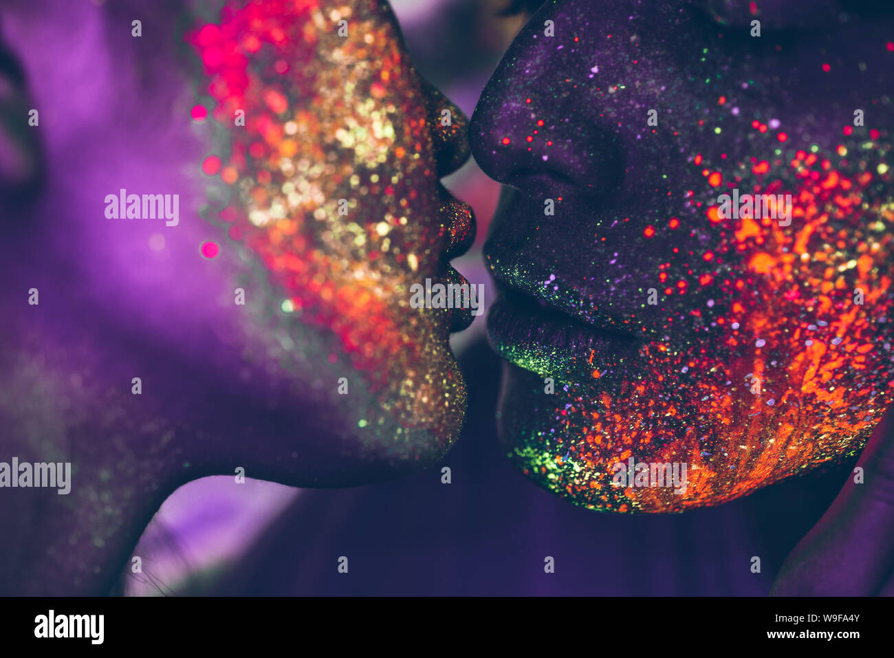 Couple kissing in the disco club with fluorescent paintings on the faces Stock Photo