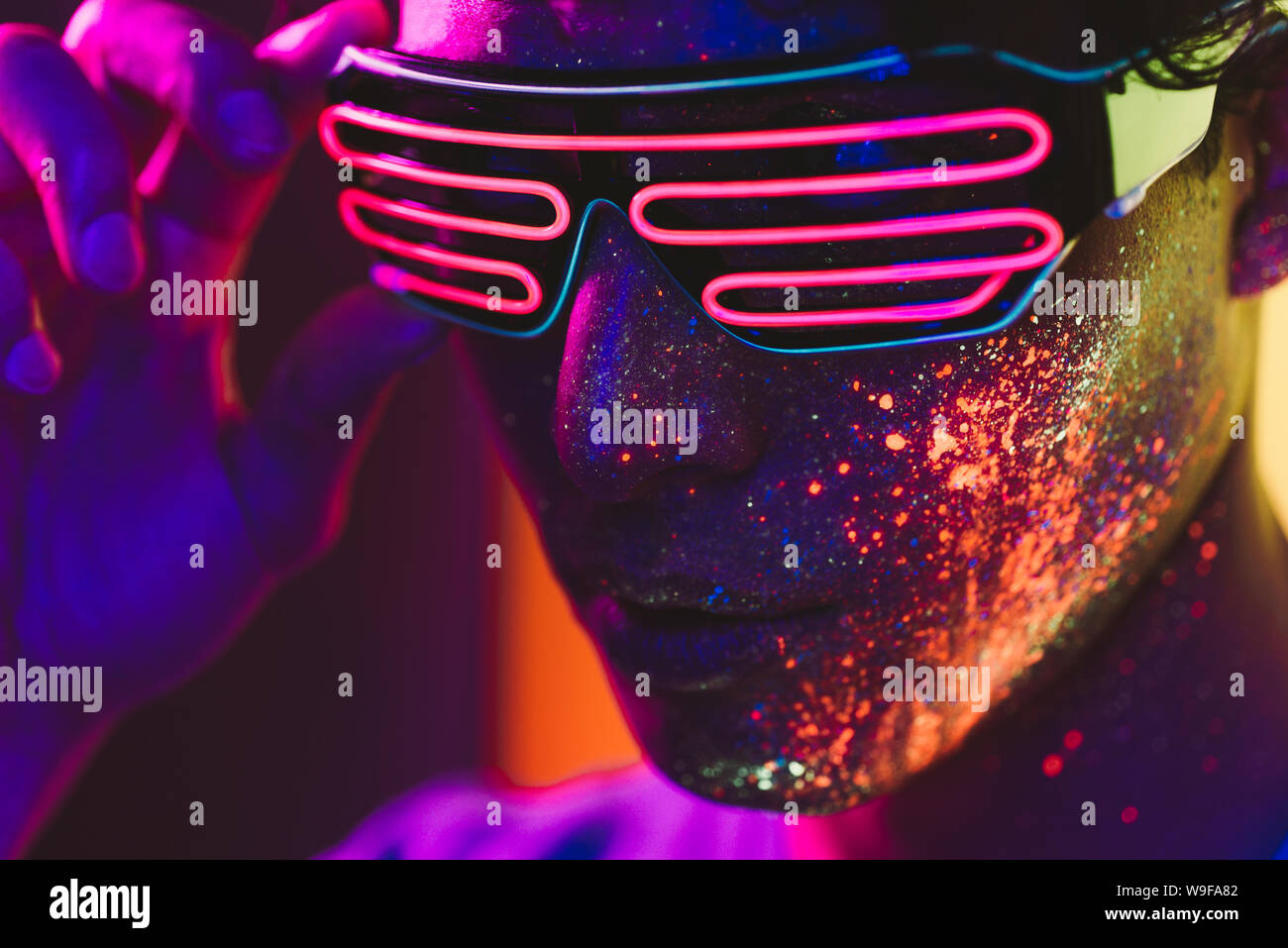 Handsome boy dancing at the rave party with fluorescent paintings on ...