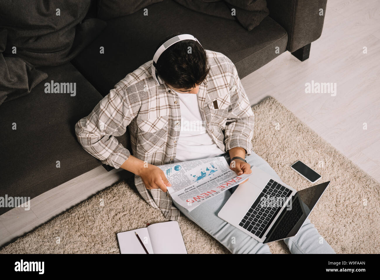 overhead view of young man reading fake news newspaper while sitting on ...