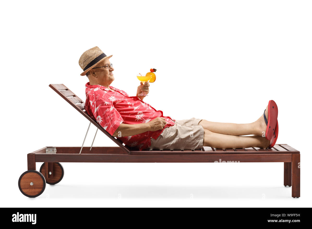 Full length profile shot of a mature man holding a cocktail and relaxing on beach bed isolated on white background Stock Photo