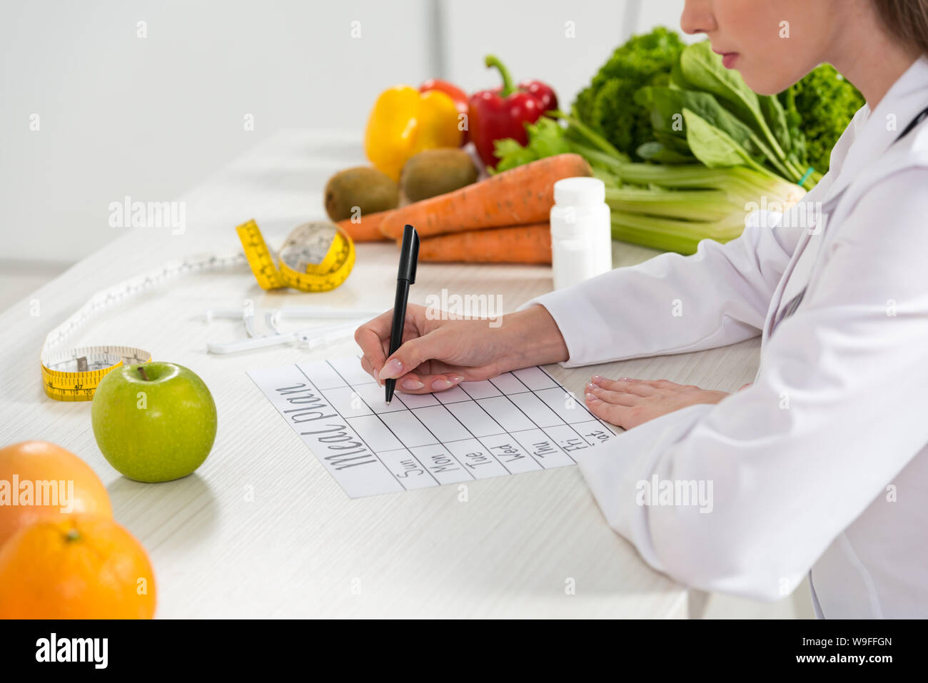 cropped view of dietitian writing in meal plan at workplace Stock Photo
