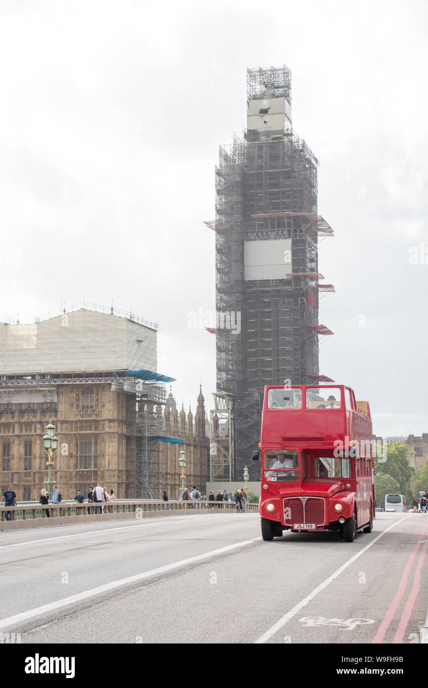 A vintage heritage red London bus with a scaffolding covered Big Ben / Elizabeth tower at the background Stock Photo