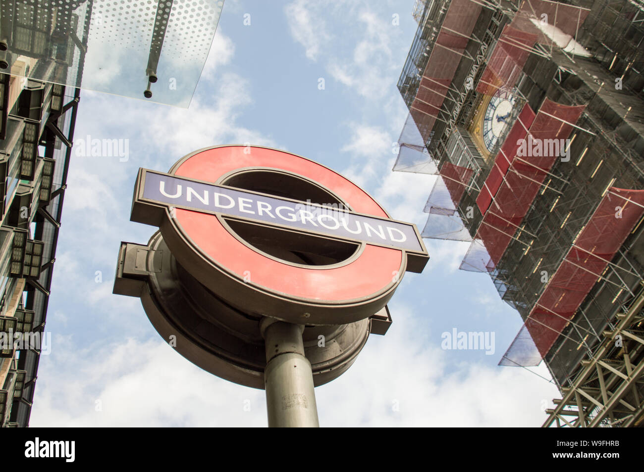 London Underground symbol outside Westminster station with a view of scaffolded Big Ben Stock Photo