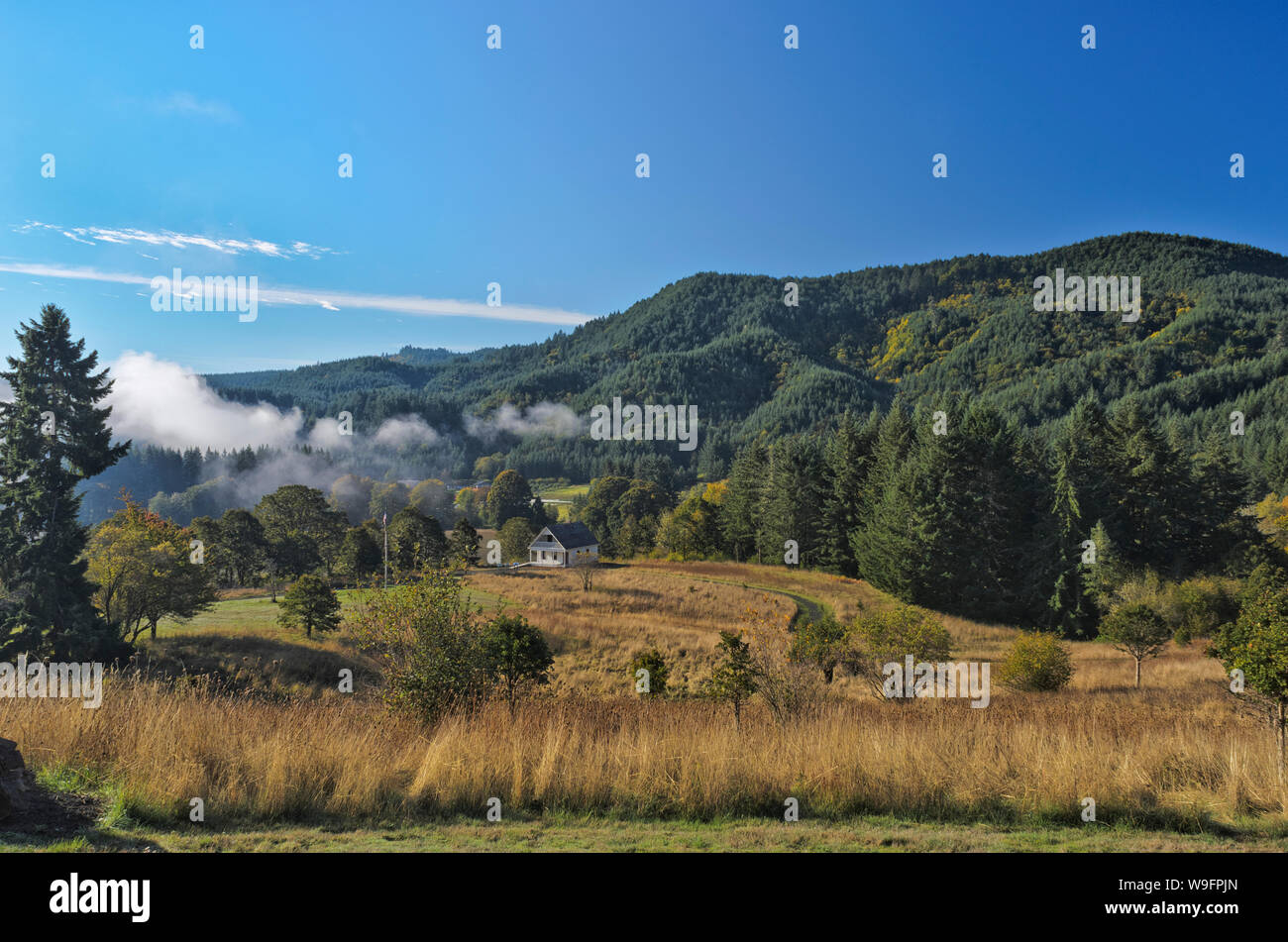 Fort Hoskins Historic County Park, near Hoskins, Oregon, in the Coast Range. Wide view over the farm museum towards fog breaking over the mountains. Stock Photo