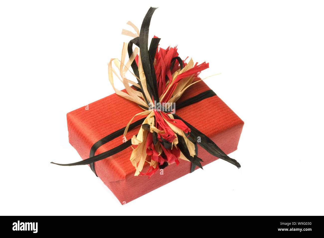 A gift wrapped in plain red paper with a raffia bow are set on a white background. Horizontal shot. Isolated on white. Stock Photo