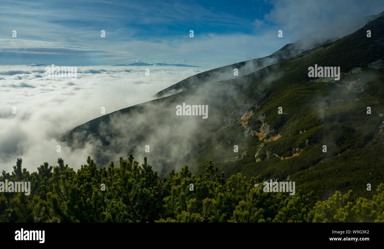 High mountains, covered by a veil of clouds. Above the clouds. Stock Photo