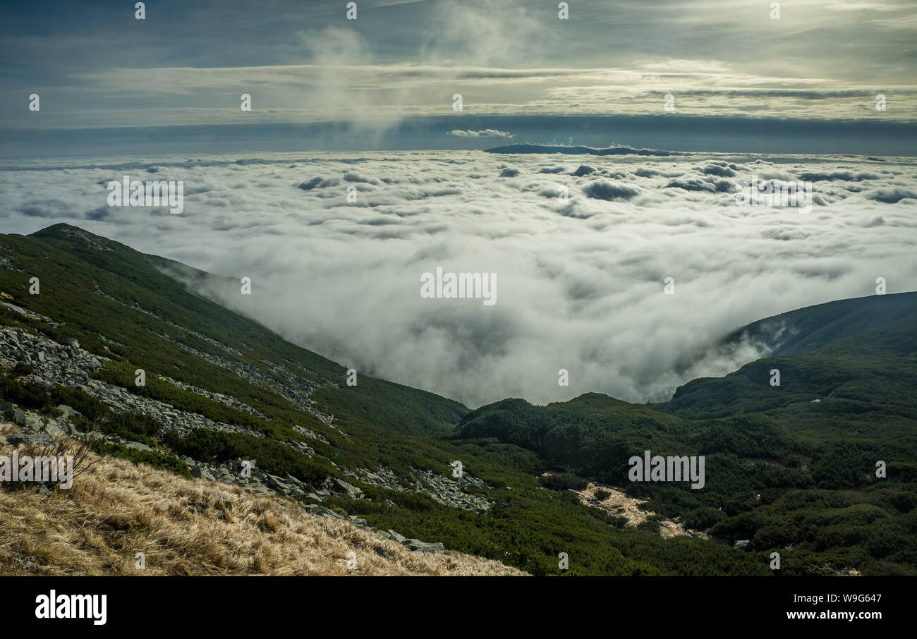 High mountains, covered by a veil of clouds. Above the clouds. Stock Photo