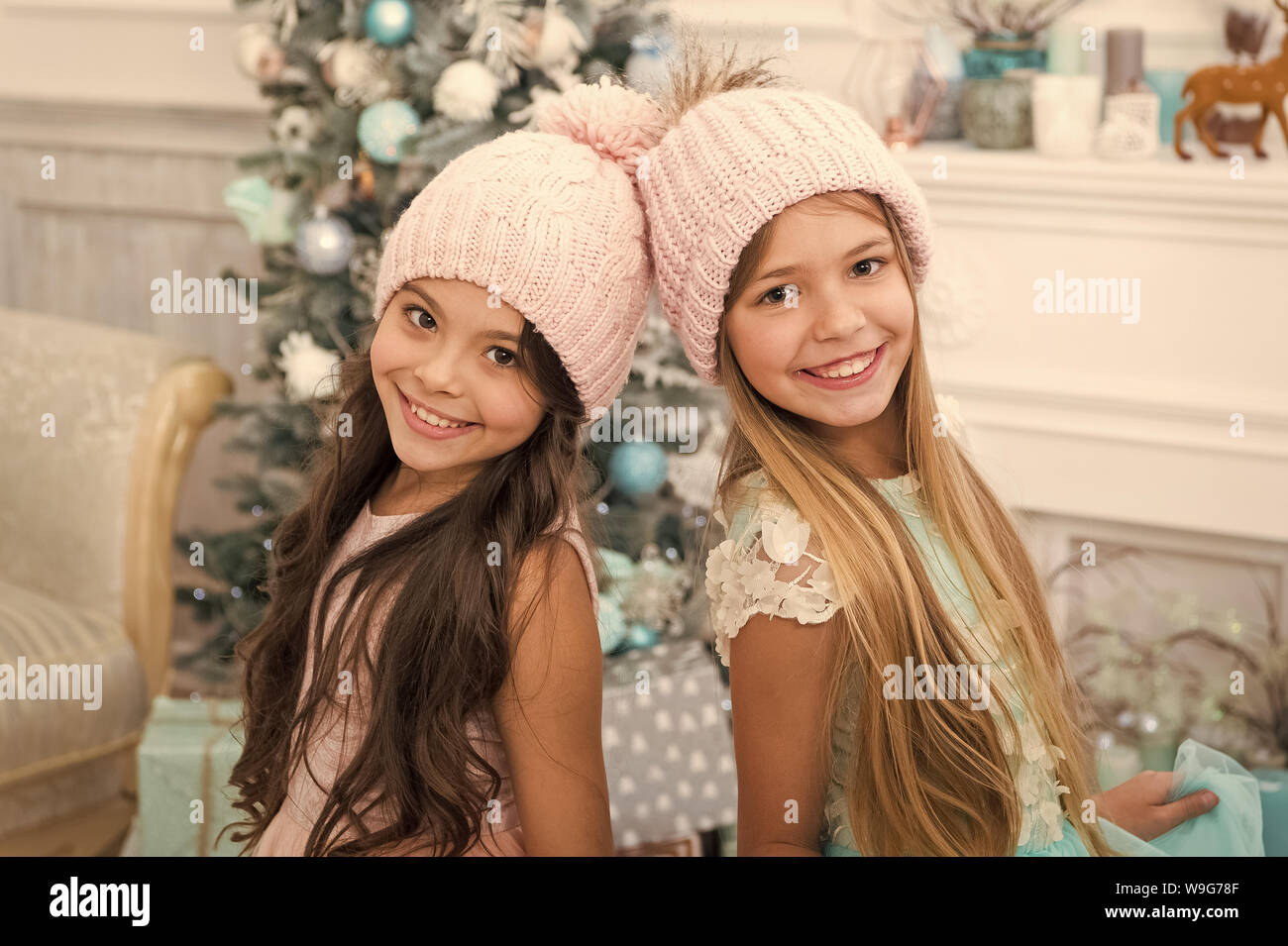 Trendy Girls Winter Season Accessory Children Wear Knitted Hats Girls Long Hair Happy Smiling Faces Christmas Tree Background Kids Wear Warm Soft Knitted Pink Hats Fancy Knitted Hats For Girls Stock Photo