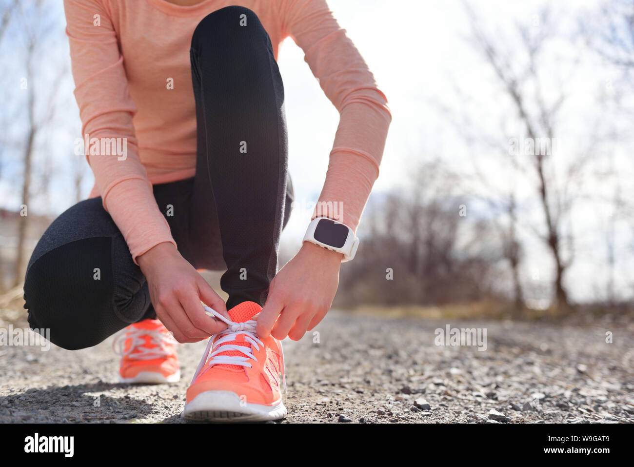 Running shoes and runner sports smartwatch. Female runner tying shoe laces  on running trail using smart watch heart rate monitor Stock Photo - Alamy