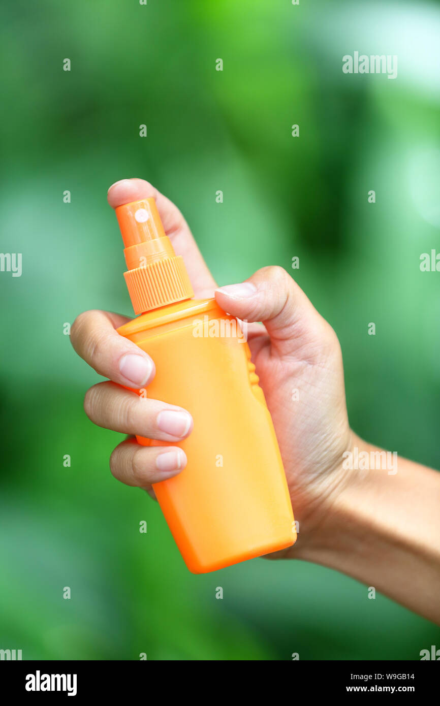 Mosquito repellent. Woman spraying insect repellent for skin outdoor in