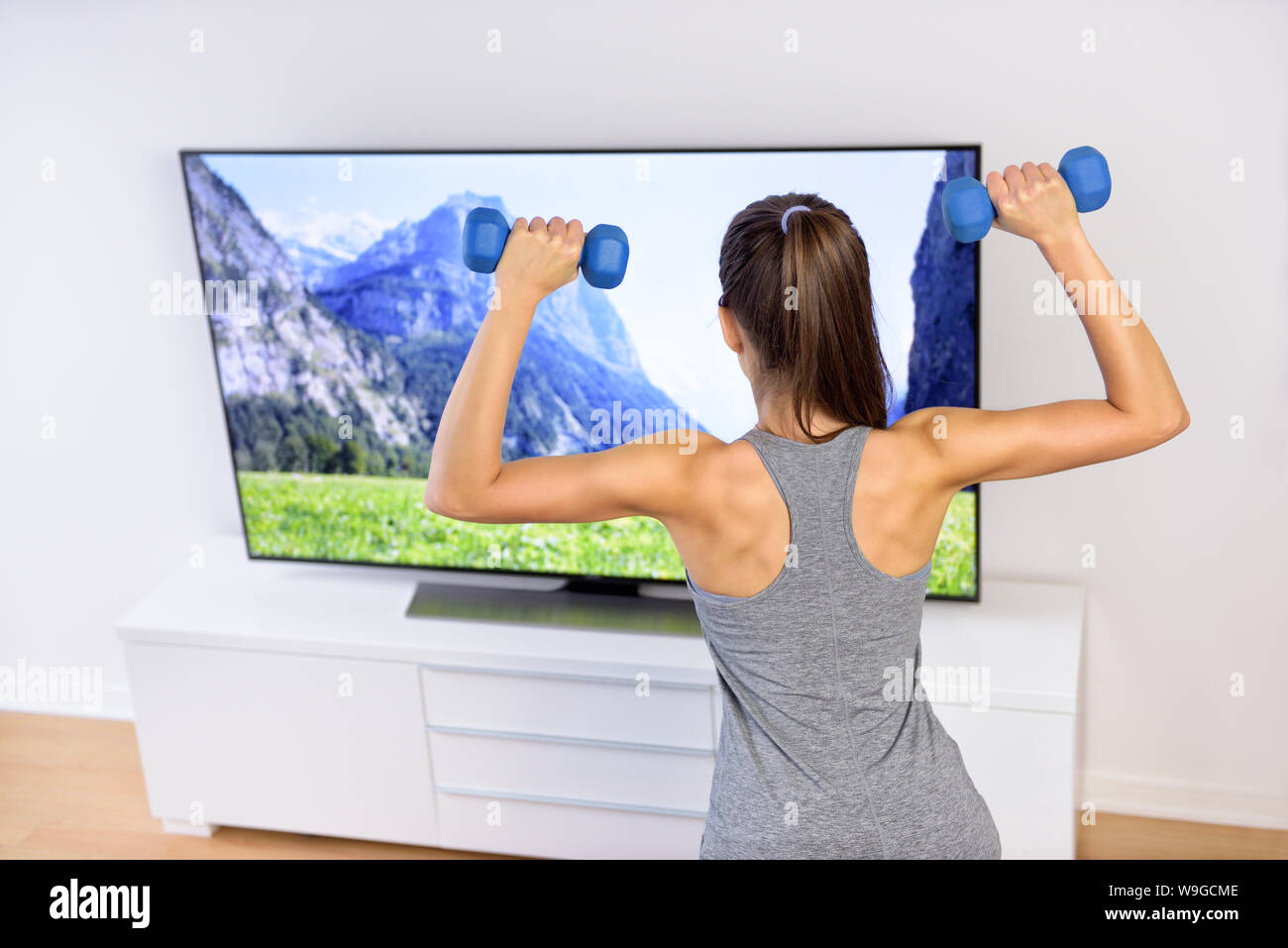 Fitness at home woman working out in front of tv. Back of a young