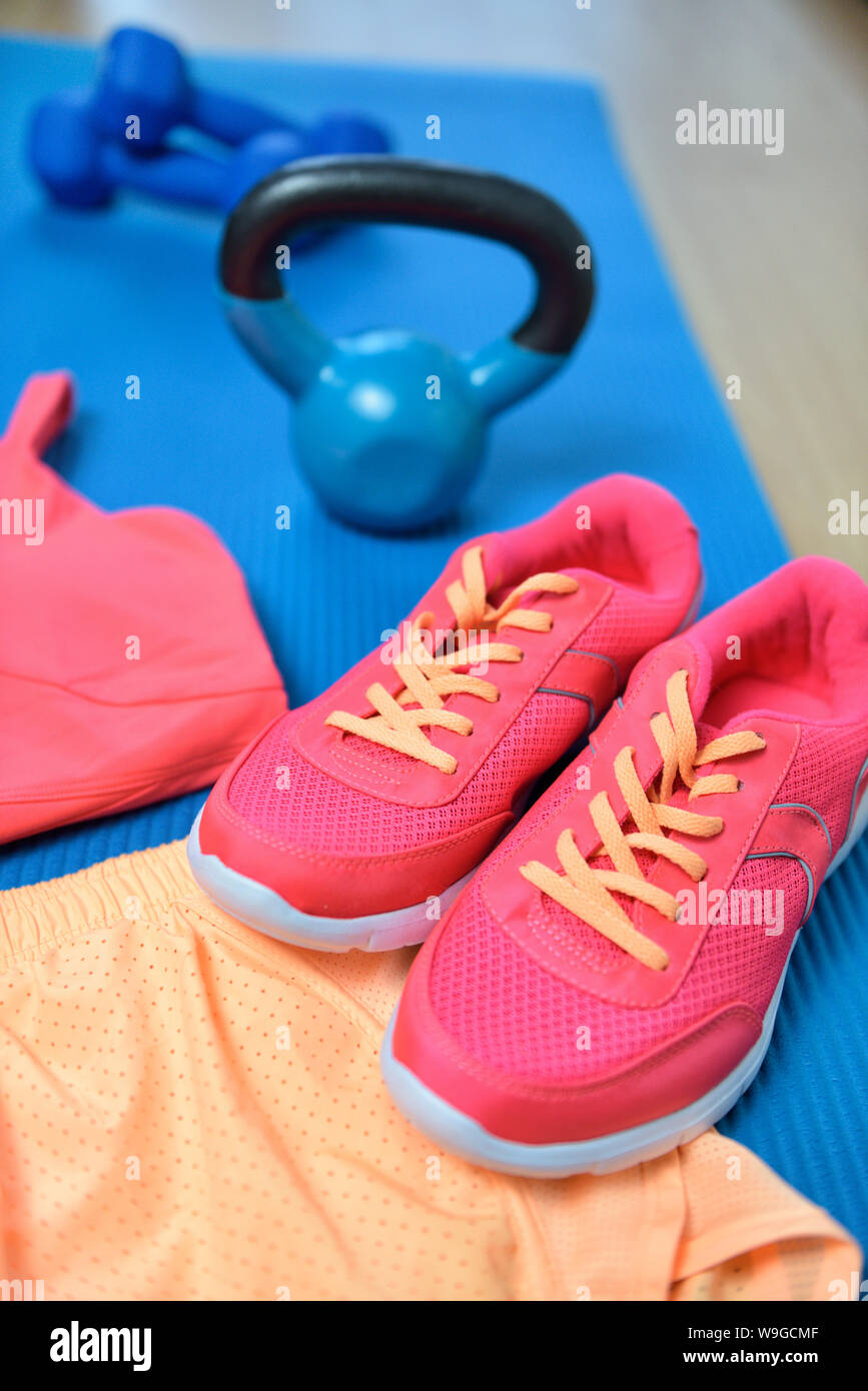 Gym shoes - Fitness outfit closeup with kettlebell. Crossfit clothes on yoga mat in pink color with weights the background the floor. Fashion activewear clothes concept Stock Photo -
