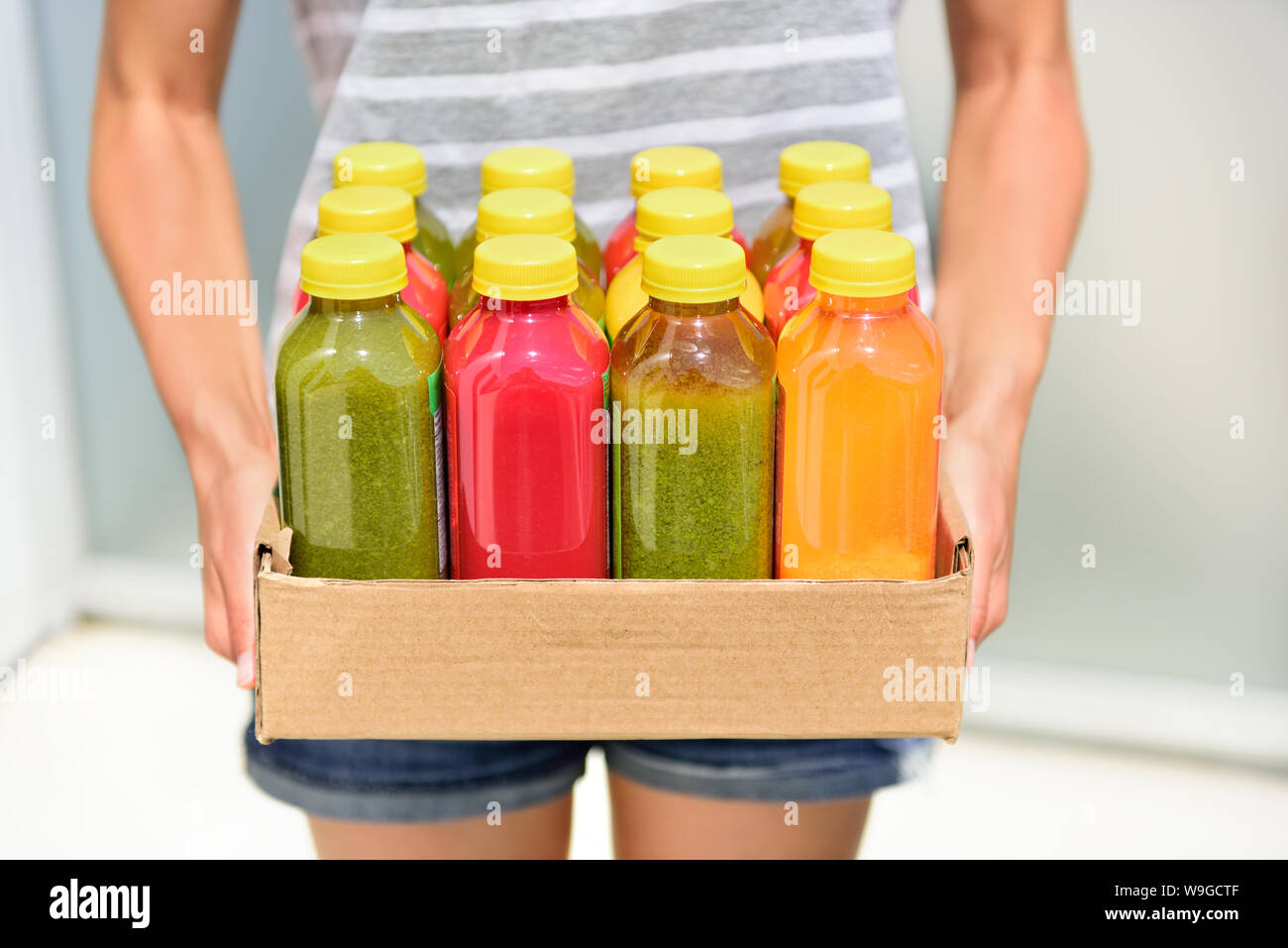 Juicing cold pressed vegetable juices for a detox diet. Dieting by cleansing your body from toxins with raw organic fruits and vegetables juice made fresh and delivered in bottles. Stock Photo