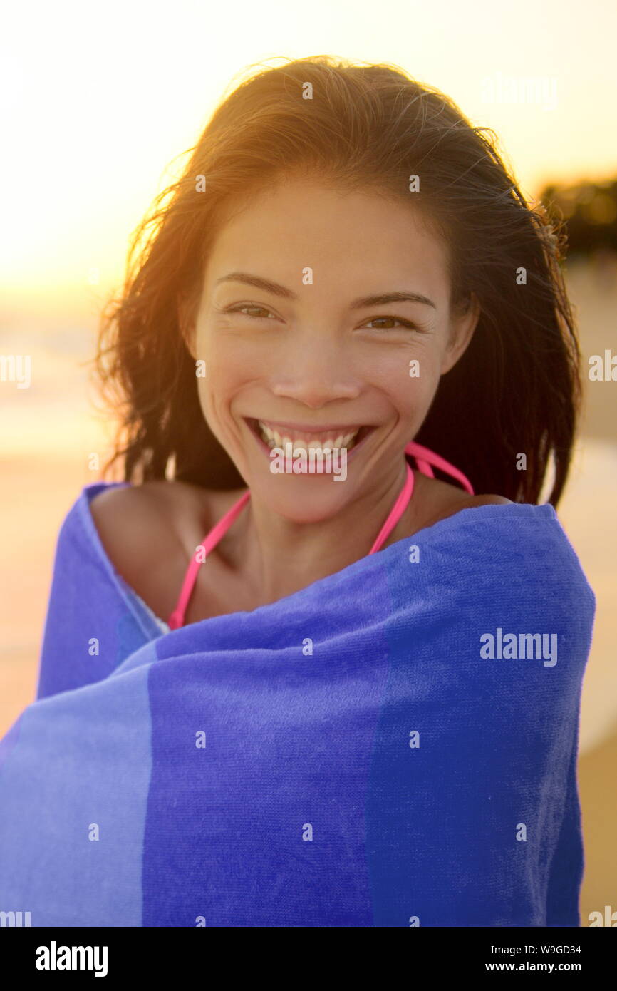 Portrait of happy young woman wrapped in towel drying after swimming in